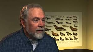 A man in front of a poster with many birds.