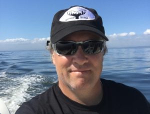 A man wearing sunglasses and a hat on the water.