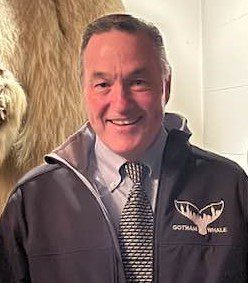 A man in a jacket standing next to a bear.